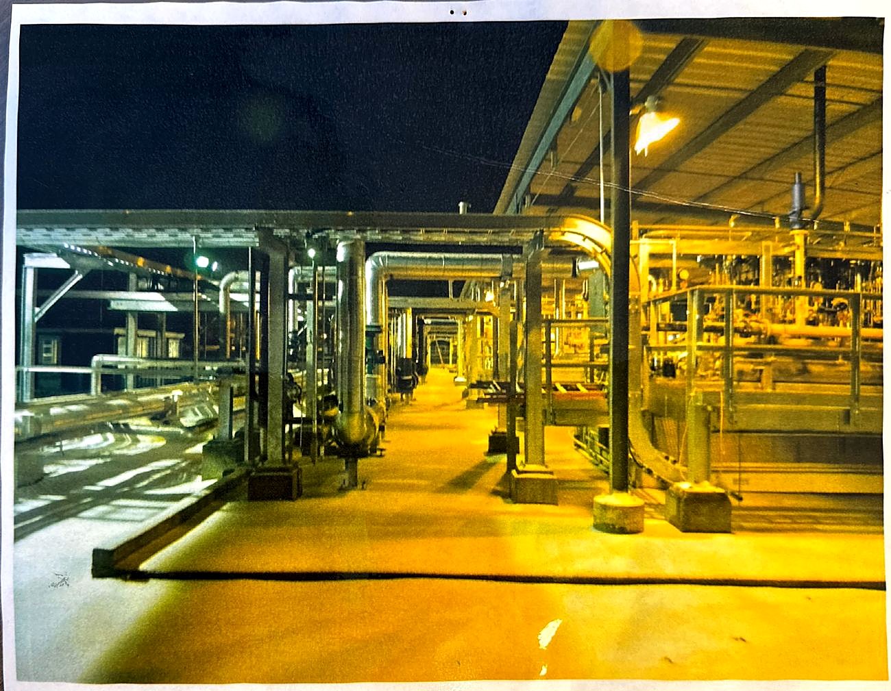 Stainless LNG piping under a pipe shed at night